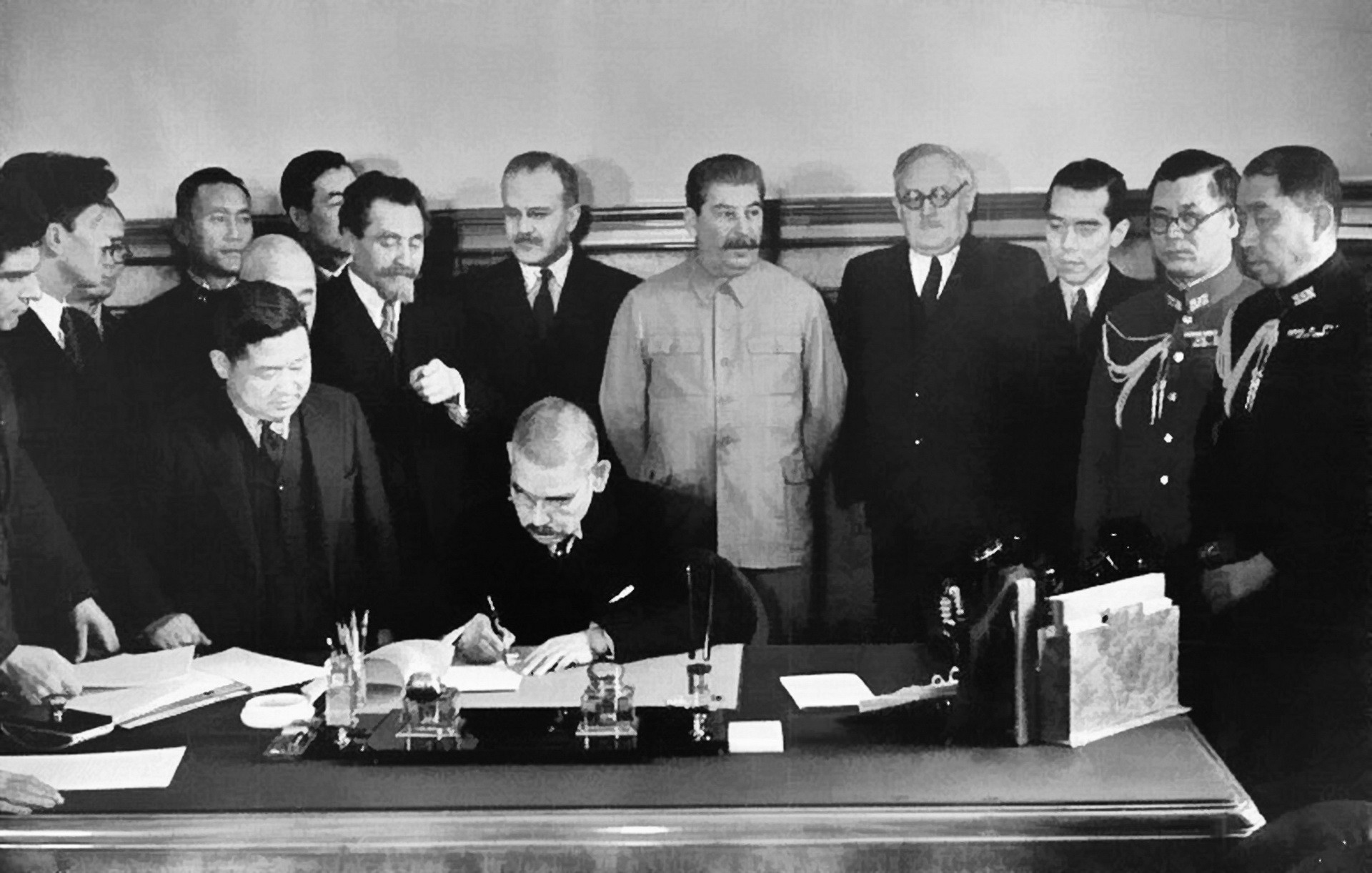 Зов Мира... На другой фотографии те же лица, только за столом сидит Мацуока. Он старательно выписывает иероглифы под советско-японским пактом о нейтралитете.